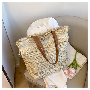 Detailed macro view of woven straw tote bag texture and brown leather straps on a sofa