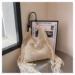 Detail of cream crochet tote bag featuring long cotton fringes and black leather strap