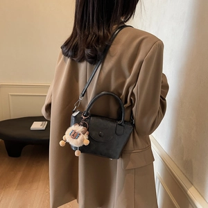Mini sac à bandoulière noir chic avec gaufrage tendance et charmant pendentif lion en peluche