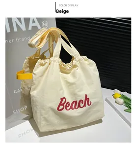 Detail of yellow canvas tote bag featuring red Beach lettering and drawstring closure