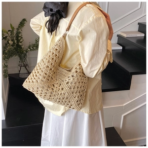 Détail du sac cabas en paille ajourée montrant la texture et la bandoulière en cuir
