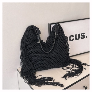 Detail of black crochet knit tote bag with long side tassels and leather shoulder strap