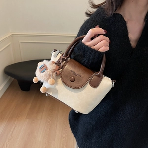Détail d'un sac à main en toile contrastée avec rabat en cuir et charm alpaga