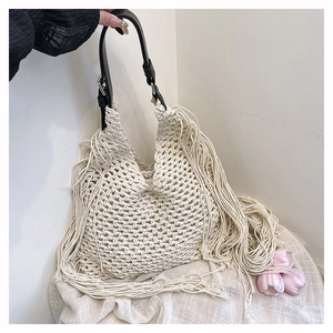Detail of hollow woven tote bag with fringe accents and adjustable leather strap