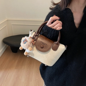 Détail d'un sac à main bicolore blanc et marron avec un charmant pendentif en forme d'agneau
