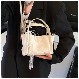 Detailed close-up of cream-white bucket bag with lychee texture and lace ribbon decor