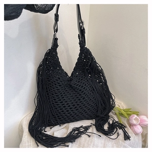 Detail of black woven tote bag with long fringe tassels and leather shoulder strap