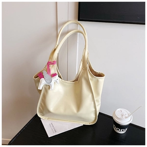 Close-up of cream tote bag featuring textured oil wax leather and a Pegasus charm