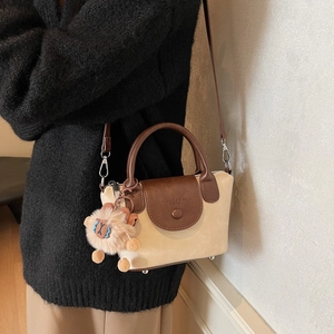 Détail d'un sac à bandoulière vintage beige et marron avec une breloque mouton en peluche