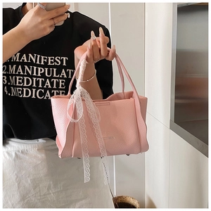 Detail of pink lychee leather bucket bag with elegant white lace ribbon handle