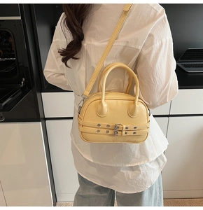 Sac Boston jaune clair porté en bandoulière sur une chemise blanche et un jean
