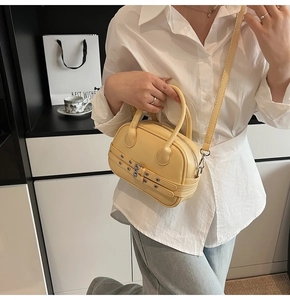 Détail du sac Boston jaune pâle avec boucles métalliques et sangles décoratives