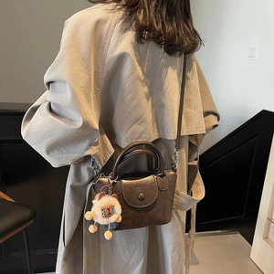 Sac à main en cuir marron sur modèle avec breloque mouton peluche et bandoulière