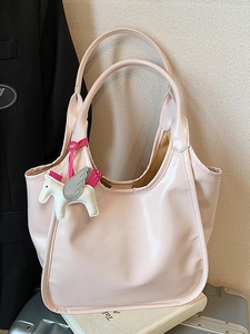 Pink waxed leather tote bag with pegasus charm placed on white books and a suitcase