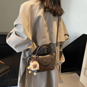 Détail du sac à main en cuir marron foncé avec breloque alpaga et bandoulière