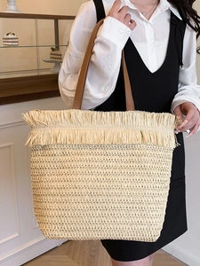 Large straw tote bag with raffia fringe and leather straps for beach vacation