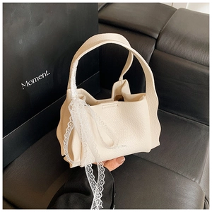 Detailed macro view of cream bucket bag showing lychee grain texture and wavy edge design