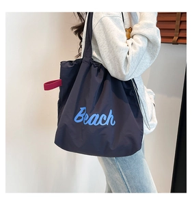 Detail of navy canvas tote bag with light blue Beach print and red accent loop