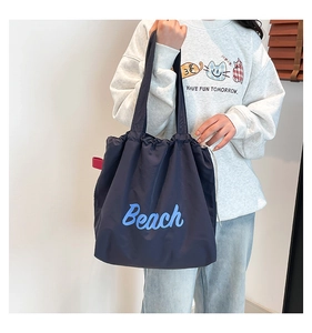 Detail of navy blue tote bag with drawstring closure and blue Beach print embroidery