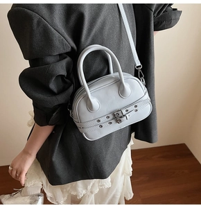 Détail d'un sac Boston bleu clair avec doubles poignées et boucles métalliques sur bandoulière