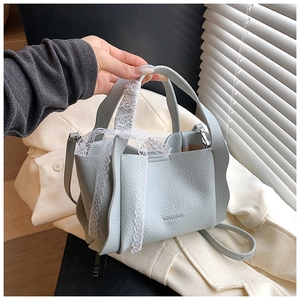 Macro shot of light blue lychee pattern leather bucket bag with white lace bow detail