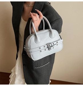 Détail d'un sac à main gris clair en similicuir avec sangles à œillets métalliques et anses