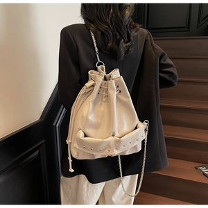 Detail of a chic cream bucket bag featuring shiny oil wax leather and metal studs