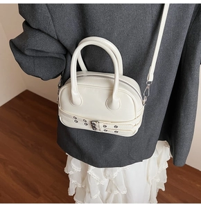 Détail du sac Boston blanc avec boucle argentée porté avec une tenue tendance