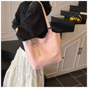Detailed view of pink leather tote bag featuring debossed logo and tassel charm on model