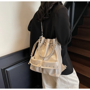 Detail shot of white bucket bag featuring silver chains and decorative punk rivets