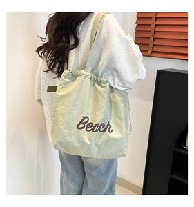 Light green nylon tote bag with brown Beach print shown on a model's shoulder