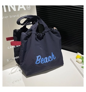 Detail of navy nylon tote bag with blue Beach text and vibrant red side webbing strap