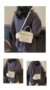 Dettaglio di una borsa a scatola bianco crema con charm a forma di pecora e finiture dorate