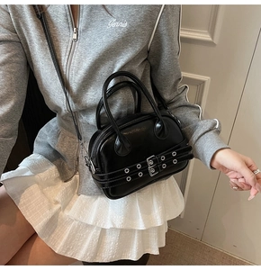 Détail du sac Boston noir brillant en similicuir avec boucles et œillets métalliques