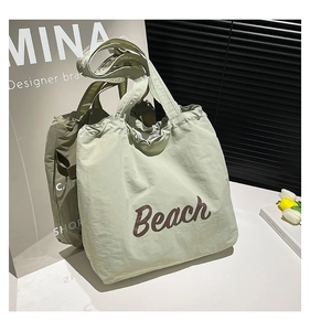Close-up of light green tote bag with crinkled fabric and Beach lettering detail