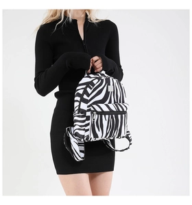 Detail shot of a zebra print canvas backpack held by a model in a black dress
