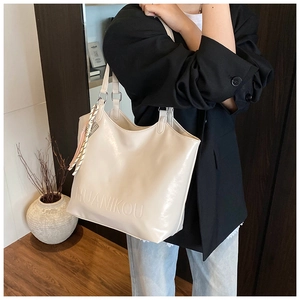 Detailed view of cream leather tote bag featuring embossed logo and decorative silk scarf