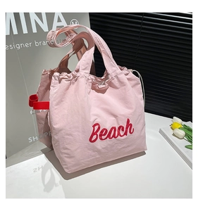 Detailed macro view of pink nylon tote bag with red Beach embroidery and side strap detail