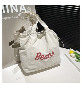 Detail of off-white tote bag featuring red Beach print and green canvas handles