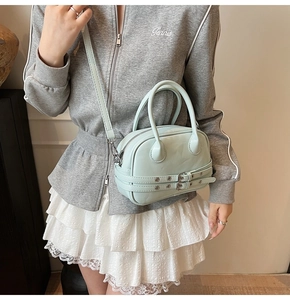 Gros plan du mini sac Boston vert menthe en cuir synthétique mat sur l'épaule du modèle