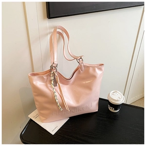 Detail of pink polished faux leather tote bag with embossed logo and tassel charm