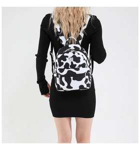 Mini backpack with black and white cow print shown worn on a model against white backdrop