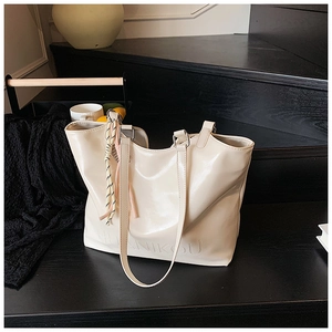 Detail of cream tote bag with HUANIKOU logo, glossy leather texture and silk scarf accessory
