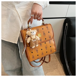 Détail d'un mini sac à dos marron vintage avec imprimés lapins et breloque ours en peluche