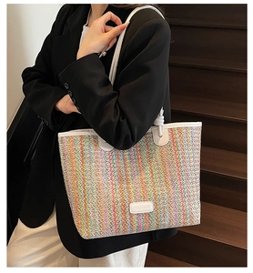 Detail of multi-color woven straw tote with white leather trim and brand patch