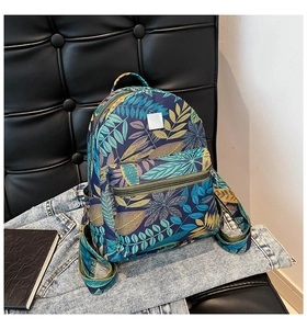 Detail of tropical plant print backpack on leather sofa with denim jacket background
