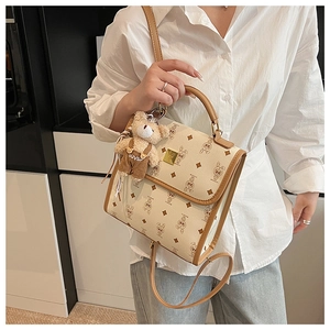 Détail du sac beige avec imprimé lapin, bordures en cuir brun et pendentif ours mignon