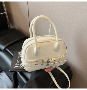 Détail du sac Boston crème avec sangles à œillets et boucles argentées en scène chic