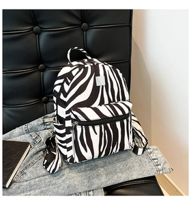 Detailed close-up of a zebra print backpack featuring silver hardware and a front zipper pocket