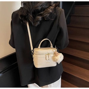 Detail of cream box handbag with ZAR&KCMK logo and a cute plush lamb charm on strap